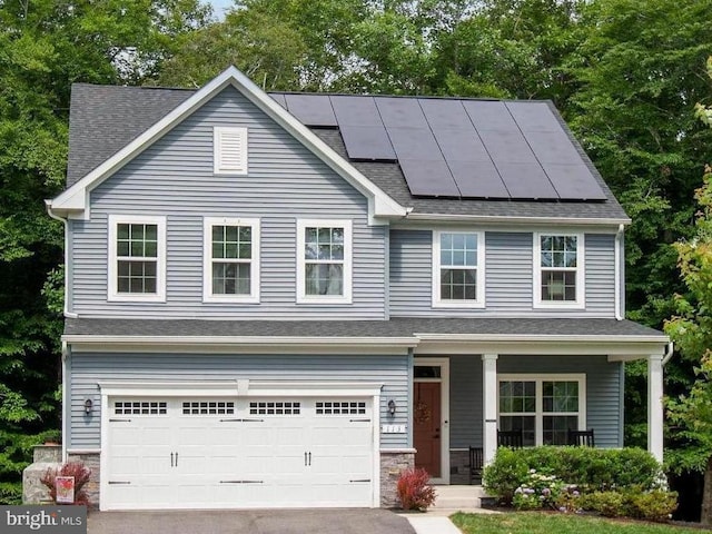 view of front of property with a garage, solar panels, and covered porch