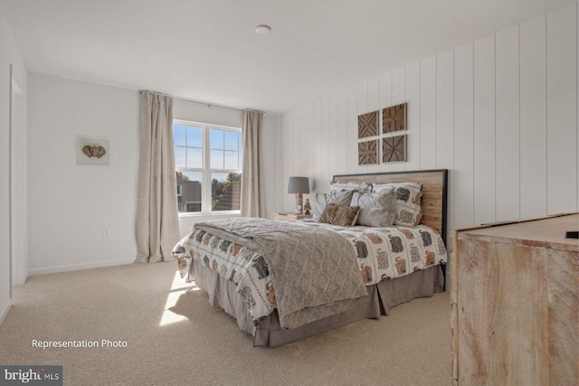 bedroom featuring light carpet and wooden walls