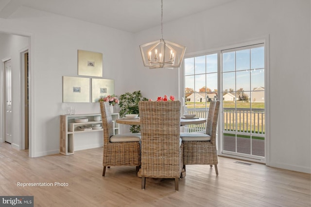 dining space with light hardwood / wood-style flooring and a chandelier