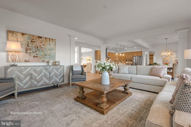 living room featuring ornate columns, beamed ceiling, an inviting chandelier, and light hardwood / wood-style flooring