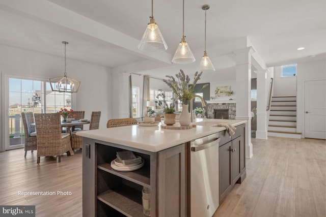 kitchen with dishwasher, a wealth of natural light, a center island with sink, and decorative light fixtures