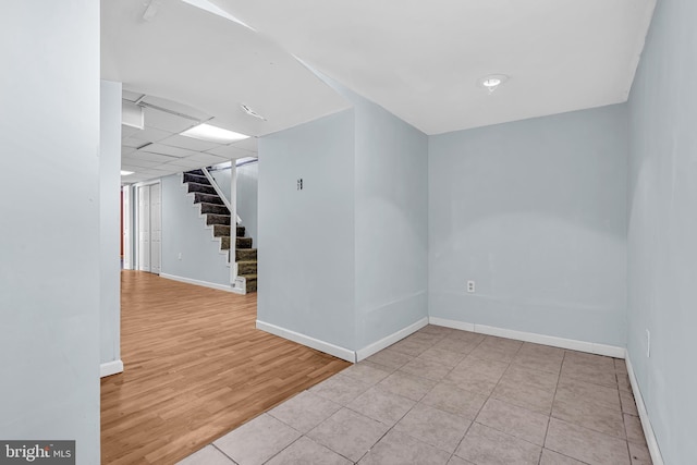 spare room featuring a drop ceiling, stairs, baseboards, and wood finished floors