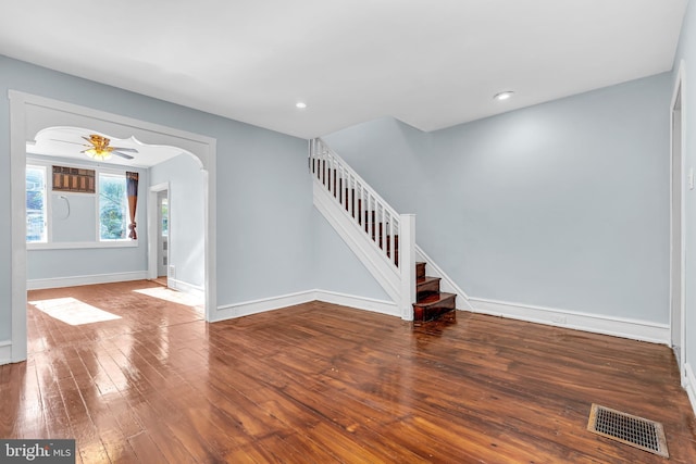 foyer featuring hardwood / wood-style floors, visible vents, baseboards, arched walkways, and stairs