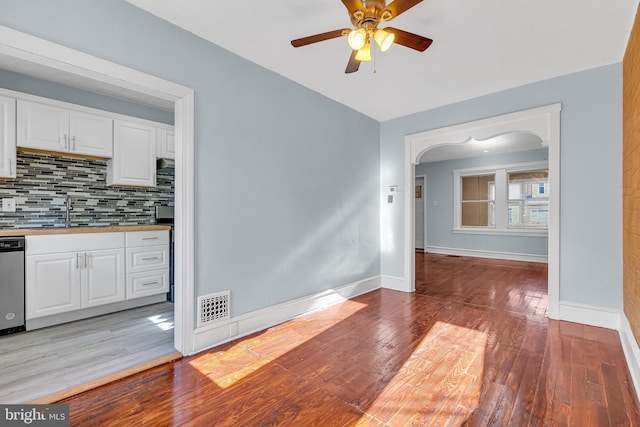 unfurnished dining area with light wood-type flooring, visible vents, baseboards, and a sink