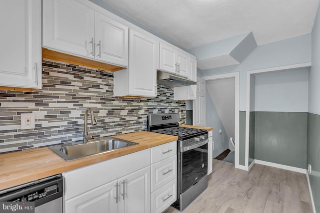 kitchen featuring under cabinet range hood, appliances with stainless steel finishes, wood counters, and a sink