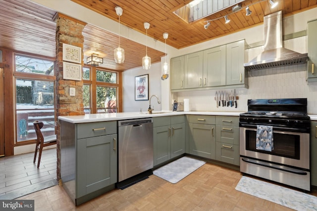 kitchen featuring pendant lighting, sink, stainless steel appliances, ventilation hood, and kitchen peninsula