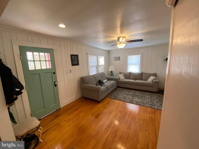 living room with crown molding, ceiling fan, and light wood-type flooring