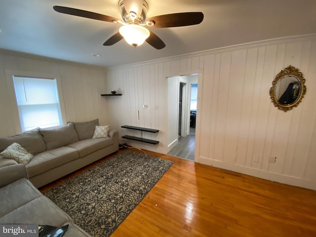 living room featuring hardwood / wood-style flooring, crown molding, and ceiling fan