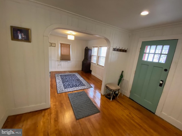 entryway with wood-type flooring, ornamental molding, and a healthy amount of sunlight