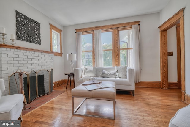 living room featuring a healthy amount of sunlight, a brick fireplace, and light wood-type flooring