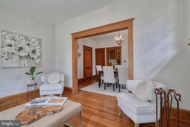 living area with a notable chandelier, baseboards, and wood finished floors