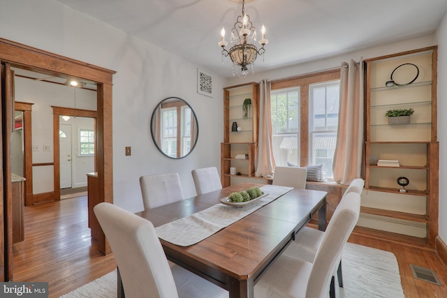 dining space with a chandelier, light wood finished floors, plenty of natural light, and visible vents