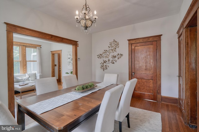 dining area with dark hardwood / wood-style floors and an inviting chandelier