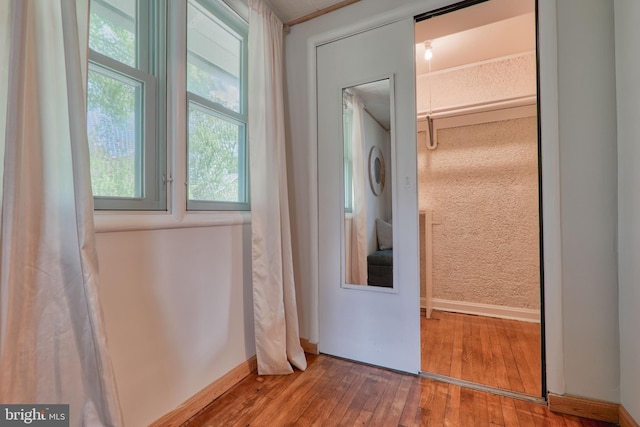 washroom featuring laundry area, stacked washer and clothes dryer, baseboards, and wood finished floors