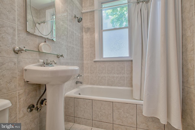 bathroom with tile walls, shower / bath combination with curtain, and a healthy amount of sunlight