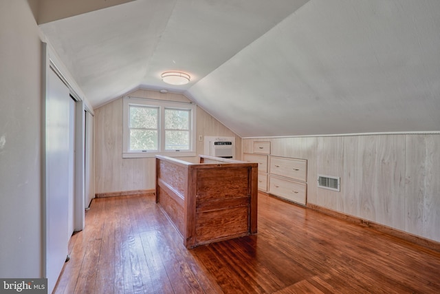 additional living space featuring lofted ceiling, visible vents, baseboards, a wall mounted AC, and light wood finished floors