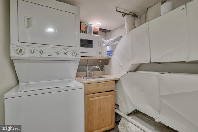 washroom featuring stacked washer / drying machine, laundry area, and a sink