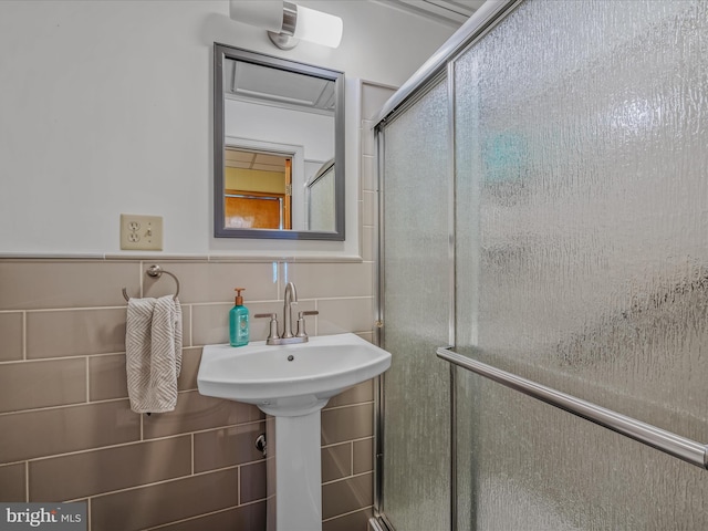 bathroom with a shower with door and tile walls