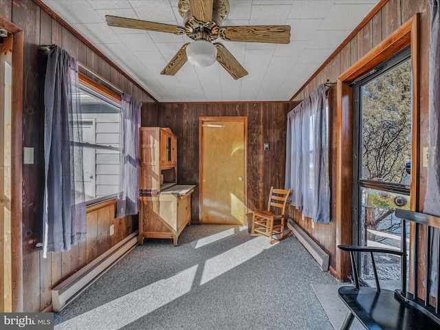 interior space with a baseboard heating unit, crown molding, wooden walls, and carpet