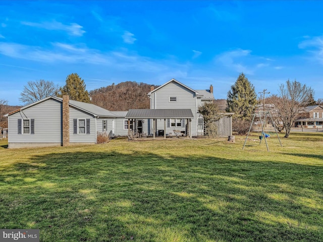 rear view of house with a playground and a lawn