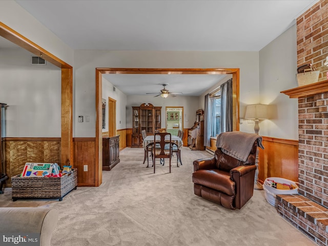 carpeted living room with ceiling fan and wooden walls