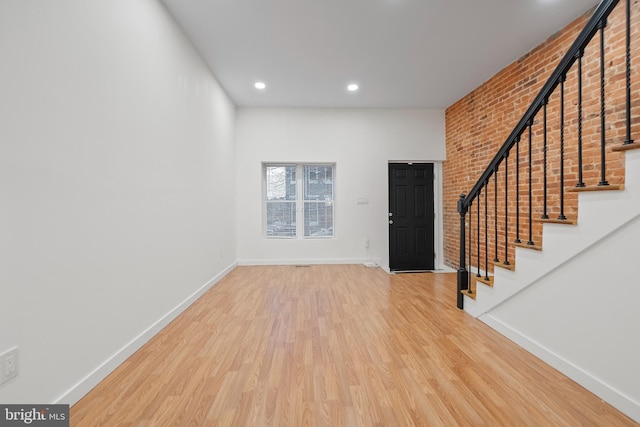 entryway with brick wall and wood-type flooring