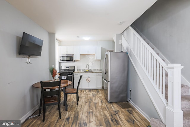 kitchen featuring stainless steel appliances, a sink, white cabinets, light countertops, and dark wood finished floors