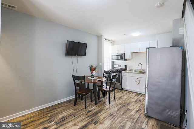 kitchen with a sink, white cabinetry, appliances with stainless steel finishes, and dark wood-style flooring