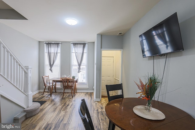 dining area with stairs, wood finished floors, visible vents, and baseboards