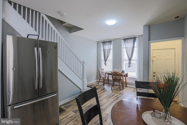 dining area with stairs, wood finished floors, visible vents, and baseboards