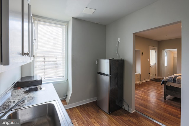 kitchen featuring freestanding refrigerator, baseboards, dark wood finished floors, and a sink