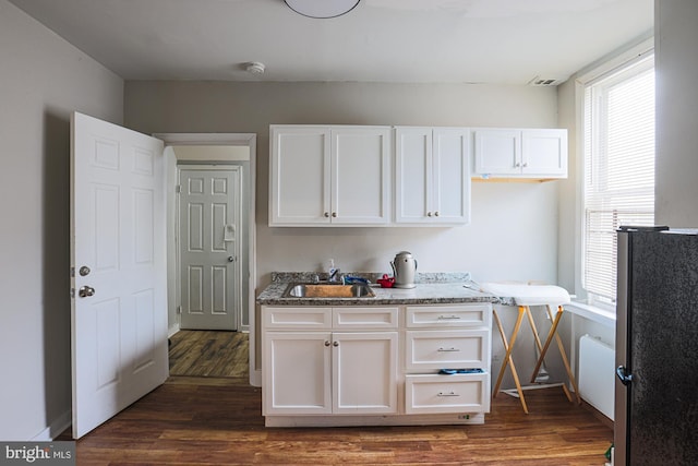 kitchen featuring dark wood finished floors, white cabinetry, and a sink