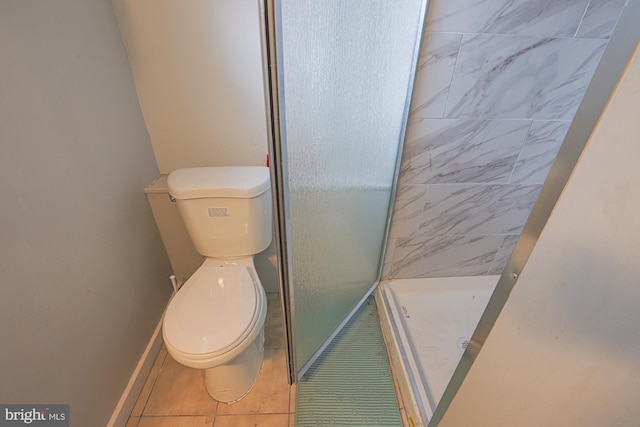 bathroom featuring toilet, a stall shower, tile patterned flooring, and baseboards