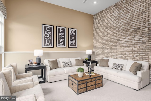 carpeted living room with brick wall