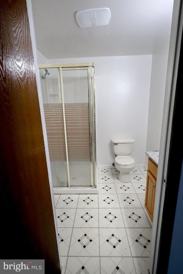 bathroom featuring vanity, toilet, an enclosed shower, and tile patterned flooring