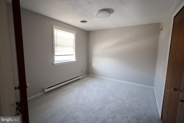 carpeted empty room featuring a baseboard heating unit