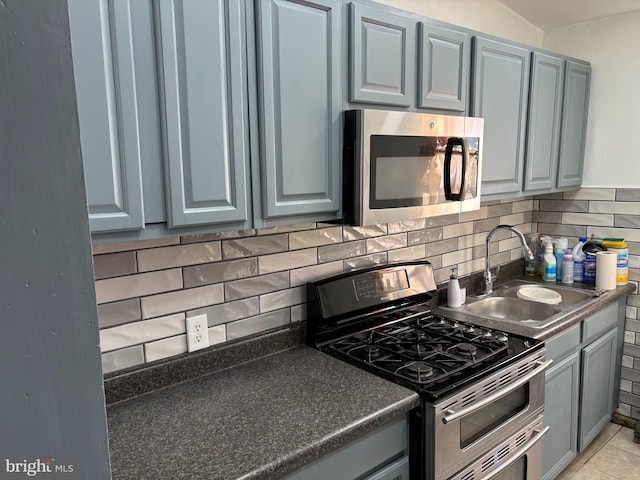 kitchen with light tile patterned flooring, appliances with stainless steel finishes, sink, and backsplash