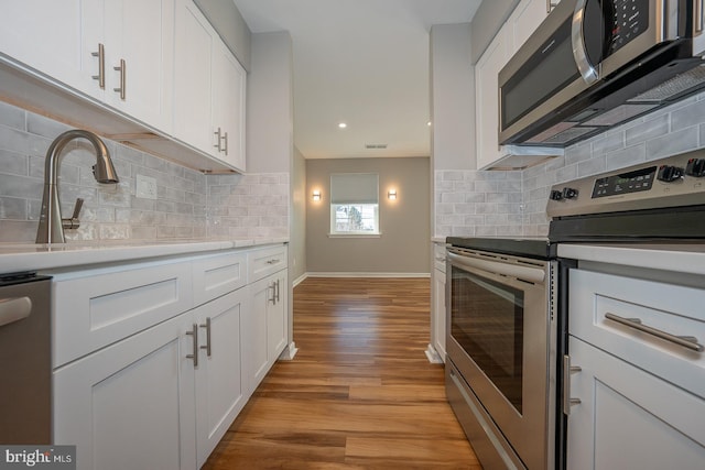 kitchen with white cabinetry, tasteful backsplash, stainless steel appliances, and light hardwood / wood-style flooring