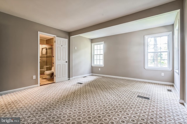 unfurnished bedroom featuring light carpet and ensuite bath