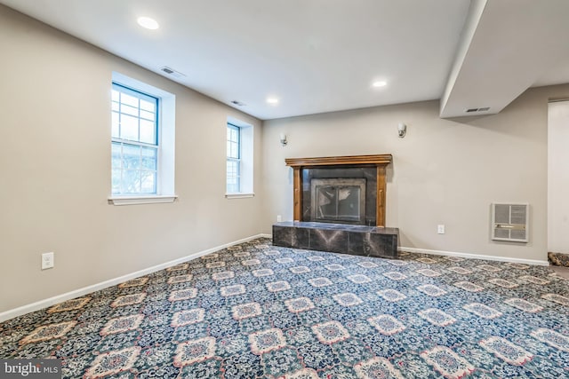 unfurnished living room featuring heating unit, a tiled fireplace, and carpet flooring