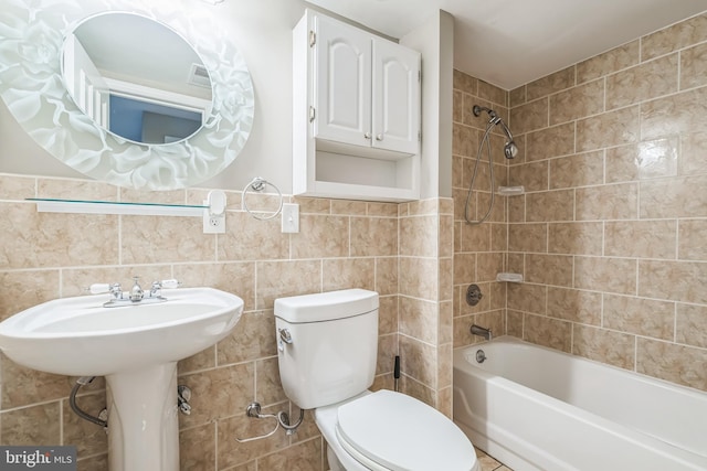 bathroom featuring tile walls, tiled shower / bath, decorative backsplash, and toilet