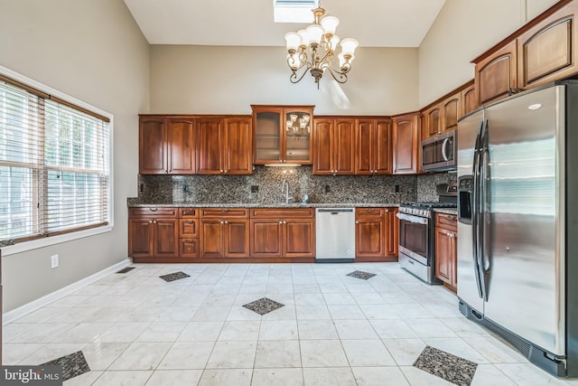 kitchen featuring light tile patterned flooring, pendant lighting, a high ceiling, stainless steel appliances, and an inviting chandelier