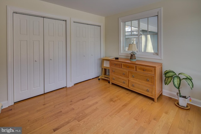 bedroom featuring light hardwood / wood-style flooring and two closets