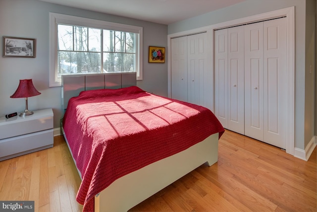 bedroom with light hardwood / wood-style floors and two closets