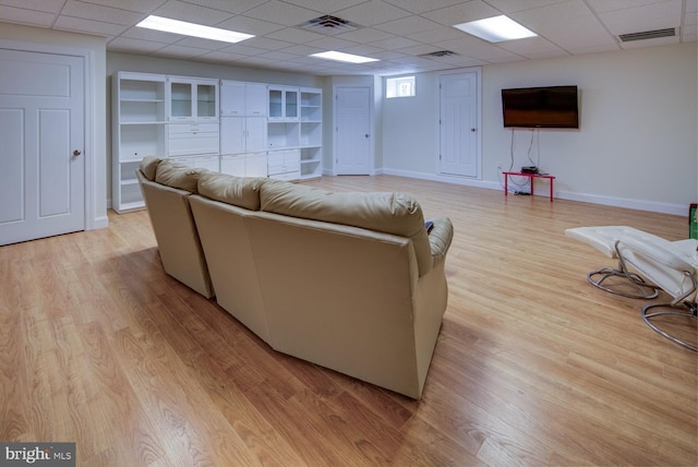 living room featuring a drop ceiling and light wood-type flooring