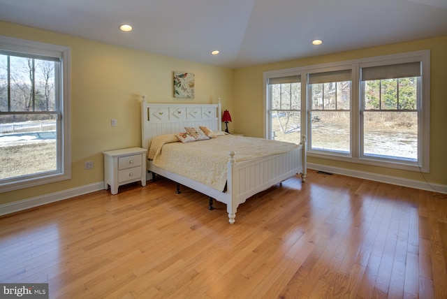 bedroom featuring lofted ceiling, multiple windows, and light hardwood / wood-style flooring