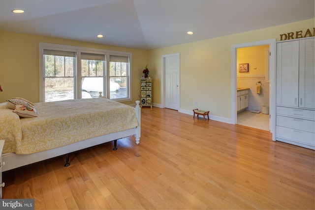 bedroom featuring lofted ceiling, connected bathroom, and light wood-type flooring