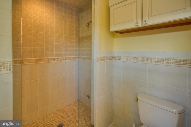 bathroom with tiled shower, toilet, and tile walls