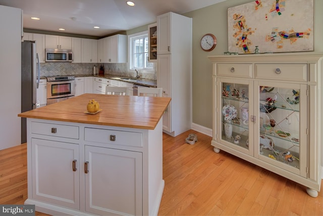 kitchen with stainless steel appliances, a center island, white cabinets, and decorative backsplash