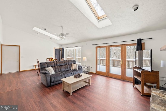 living room with dark hardwood / wood-style flooring, ceiling fan, lofted ceiling with skylight, and a textured ceiling